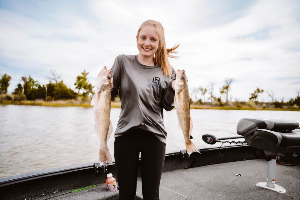 Allie holding two walleye in boat on Lake Sharpe