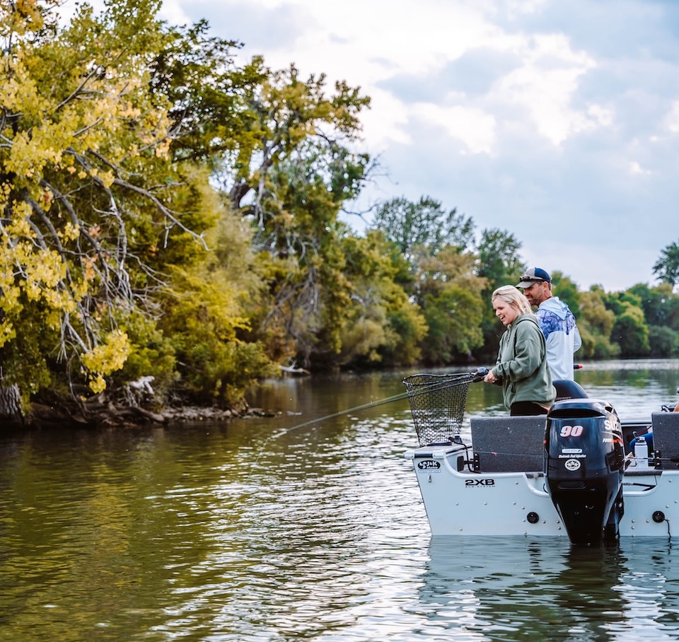 Woman reeling in fish from boat 2